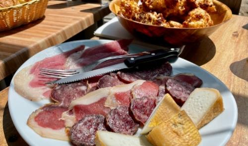 Tagliere di salumi e formaggi con pane in un ambiente rustico.