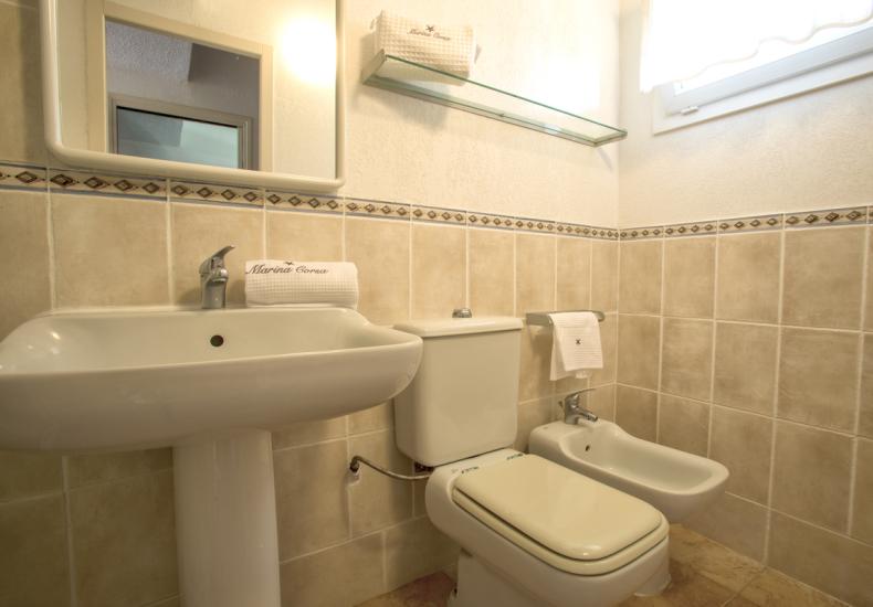 Bagno elegante con lavabo, WC e bidet, piastrelle beige.