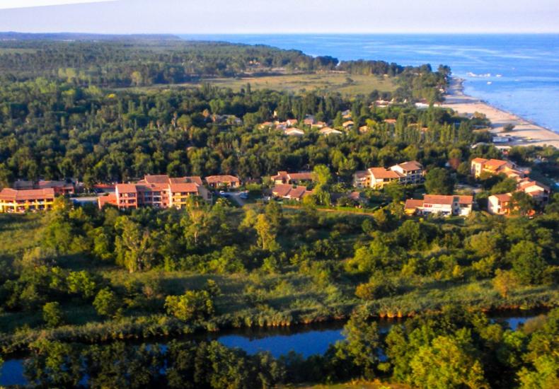 Vista aerea di un paesaggio costiero con edifici e vegetazione rigogliosa.