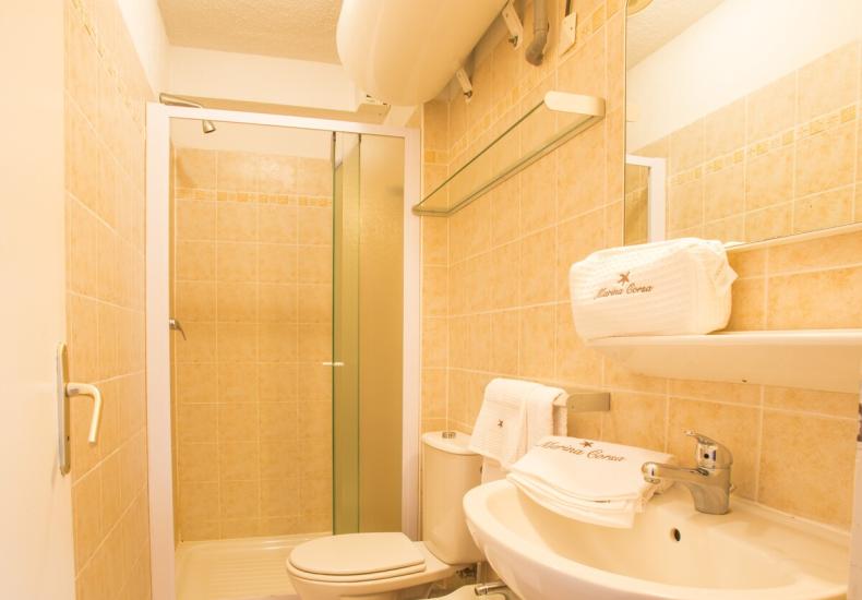 Bagno con doccia, lavabo e bidet, piastrelle beige.