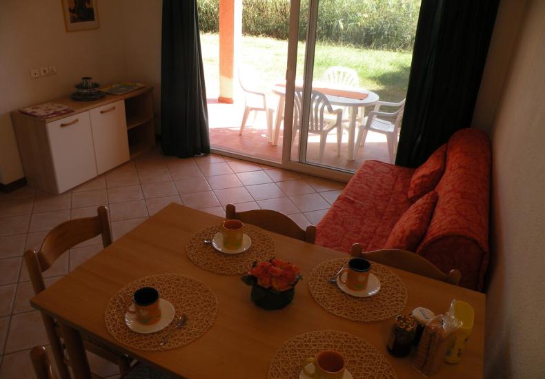 Sala da pranzo con tavolo apparecchiato e divano rosso.