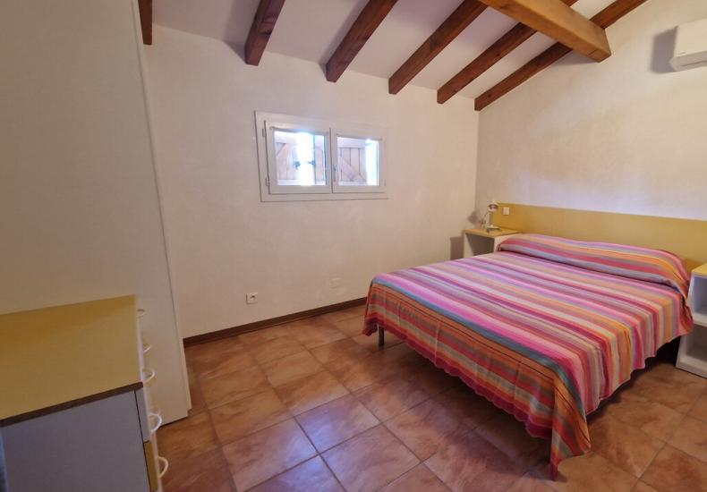 Camera da letto con letto matrimoniale e travi in legno.