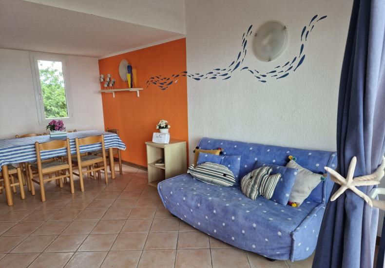 Soggiorno accogliente con divano blu e parete arancione decorata.