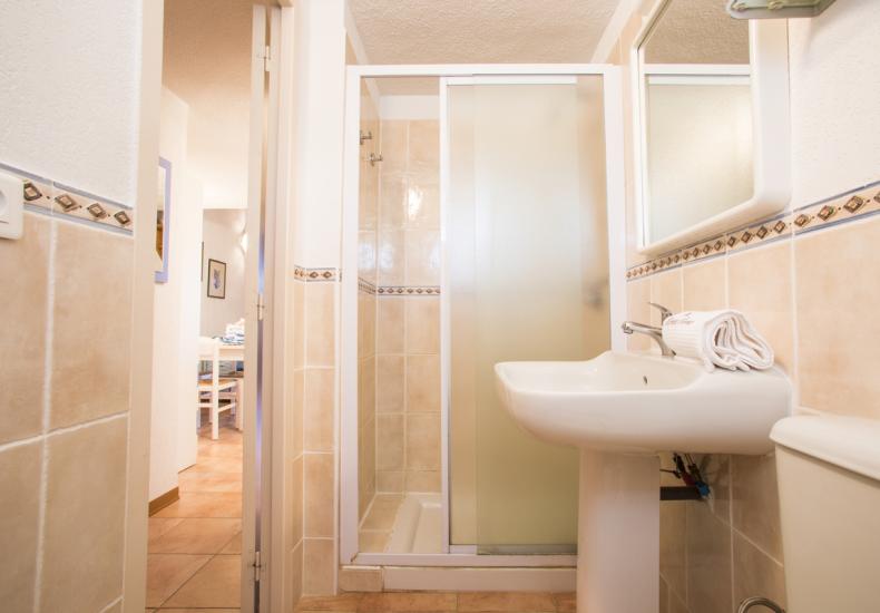 Bagno moderno con doccia e lavabo, piastrelle beige.