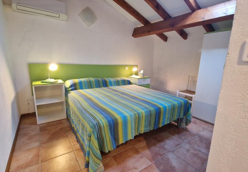 Camera da letto con letto matrimoniale e travi a vista.