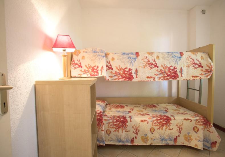 Camera con letto a castello, lampada rossa e copriletto con motivi marini.