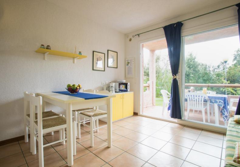 Sala da pranzo luminosa con tavolo, sedie e accesso al giardino.