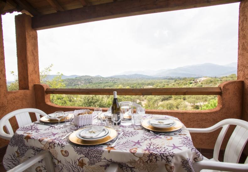 Tavola apparecchiata su terrazza con vista panoramica sulle colline.